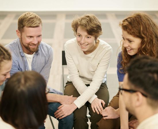 A diverse group of people smiling in a bright studio space.